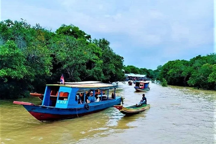 Un bateau de passagers navigue sur la rivière boueuse, entouré d'arbres verdoyants et luxuriants.