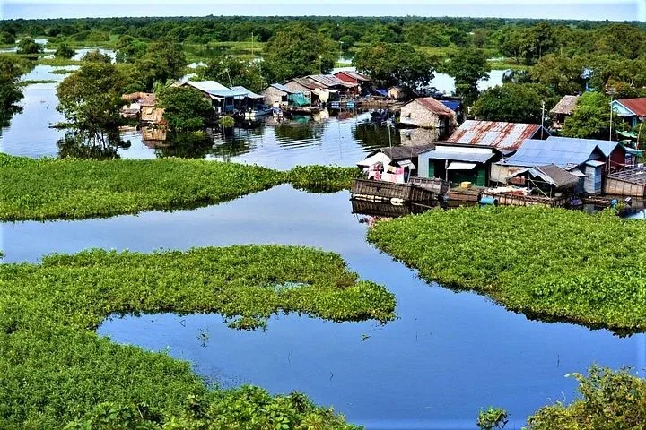 Luftaufnahme des schwimmenden Dorfes Kampong Phluk, umgeben von Wasser und üppiger Vegetation.