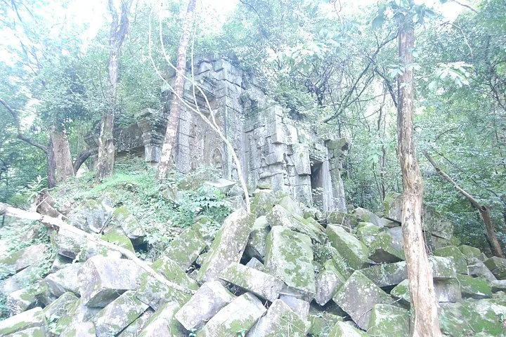 Pile of mossy stone blocks in front of an ancient temple ruin